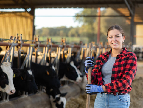 Portrait of positive woman farmer in cowshed