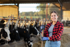 Portrait of positive woman farmer in cowshed