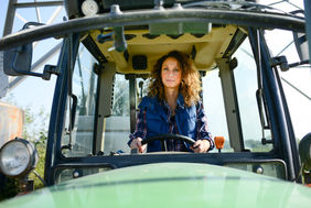 beautiful woman female farmer driving tractor in countryside field