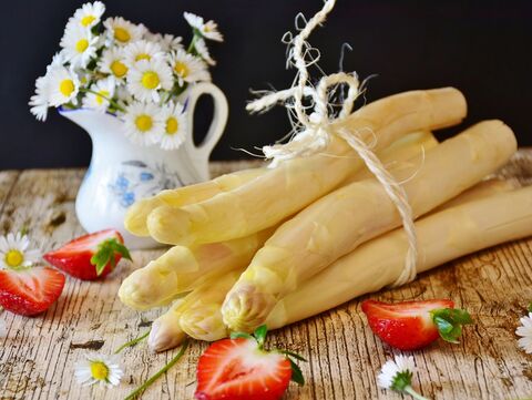Ein Bund Spargel und halbierte Erdbeeren